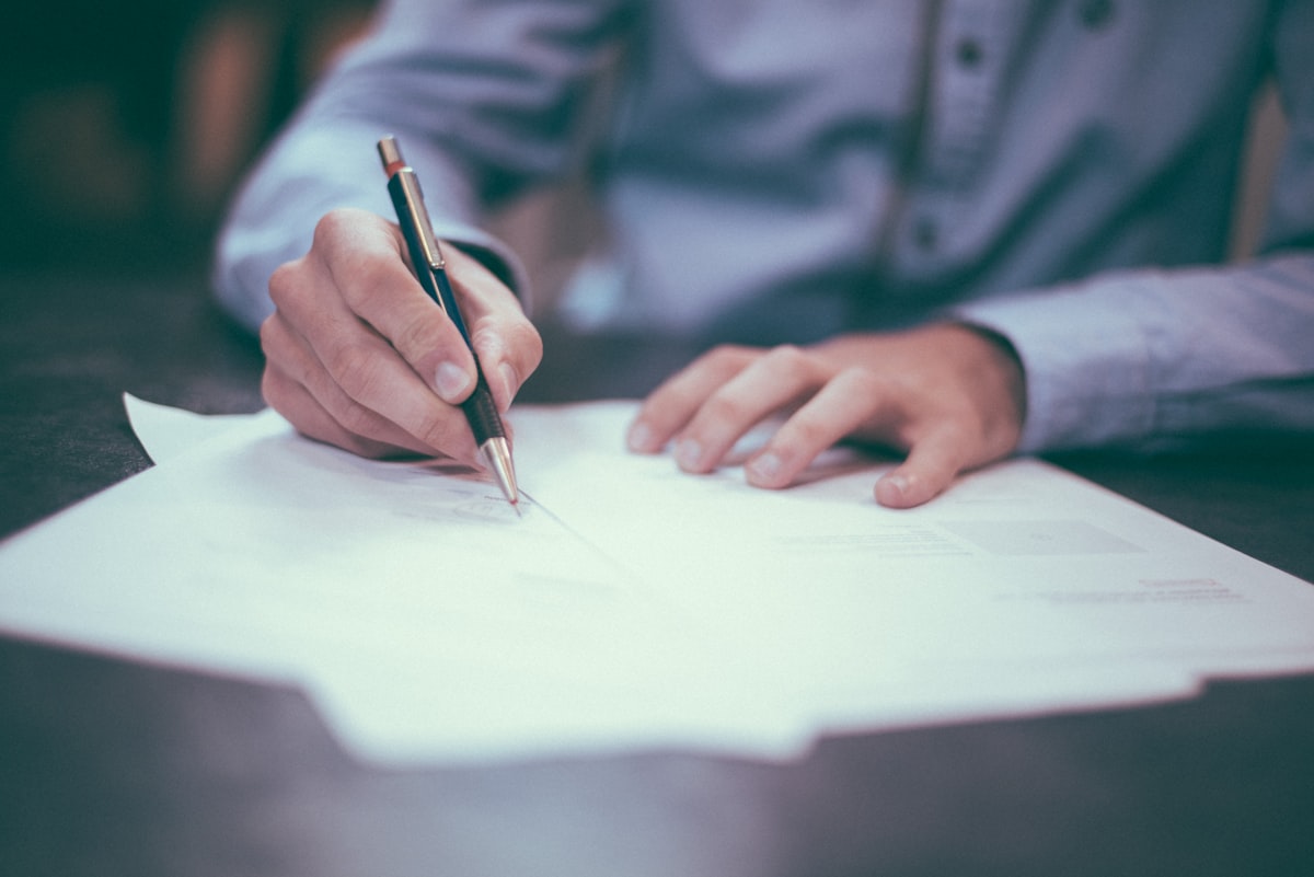 Manos firmando un contrato sobre un escritorio
